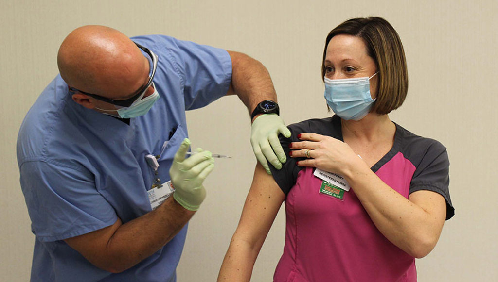 Christopher Coccari, RN administers the COVID-19 vaccine to Tara Perry, RN