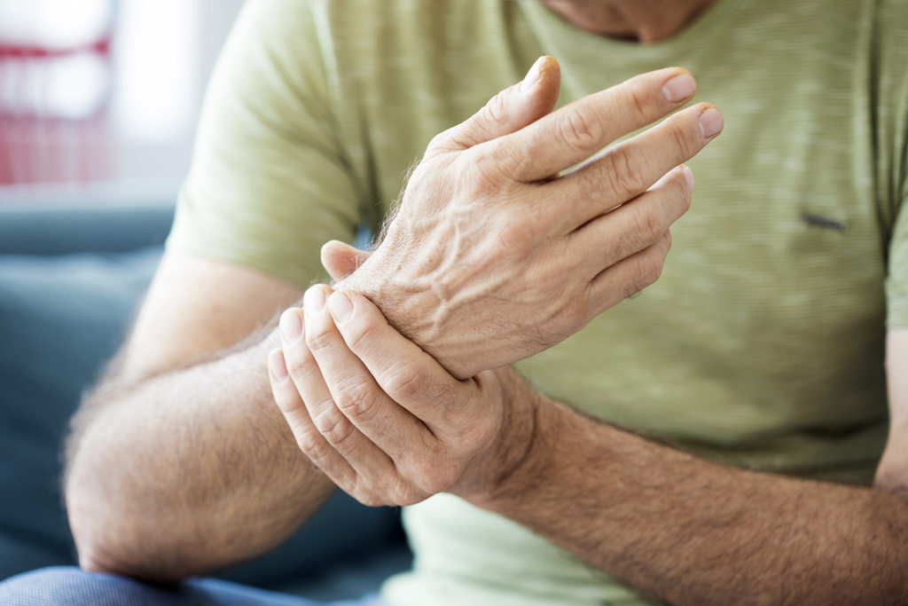 Close-up of a person holding and supporting a painful wrist joint, illustrating arthritis-related joint pain and stiffness.