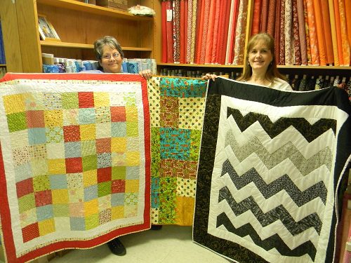 Tammy Cherry (left) and Emmy Snelick of Tangled Threads display a few of the baby quilts.